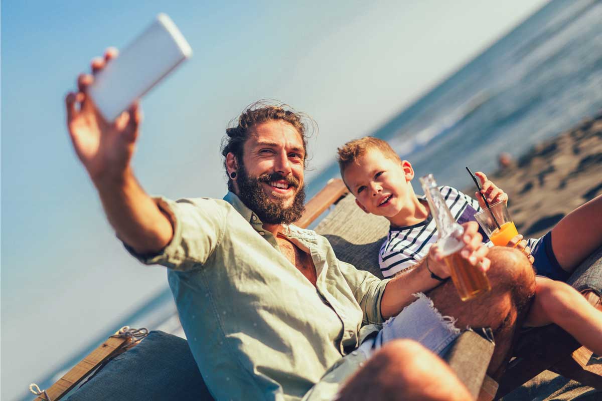 Ein Vater macht am Strand ein Selfie mit seinem Kind.